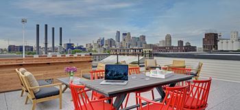Downtown skyline view from Coze Flats' rooftop with red high top chairs and rooftop firepit